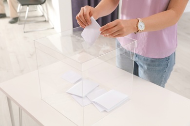 Woman putting ballot paper into box at polling station