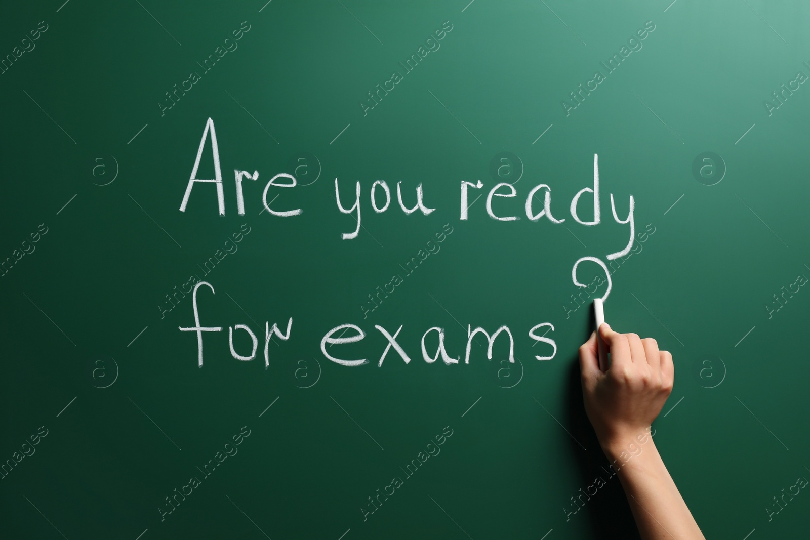 Photo of Woman writing phrase Are You Ready For Exams on green chalkboard, closeup