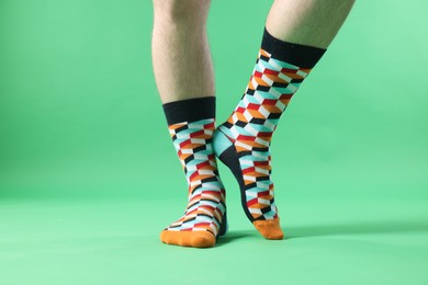 Man in stylish colorful socks on light green background, closeup