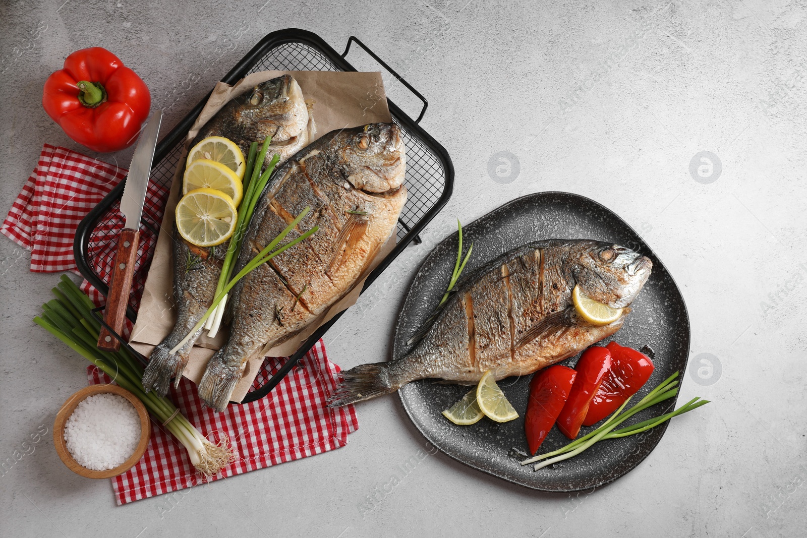 Photo of Seafood. Delicious baked fish served with green onion, bell pepper and lemon on light textured table, flat lay