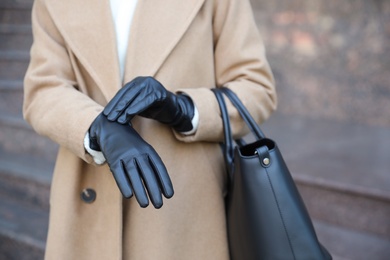 Photo of Woman with leather gloves and stylish bag on city street, closeup