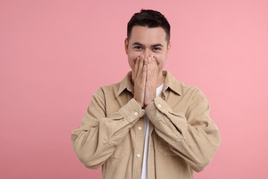 Embarrassed man covering face with hands on pink background