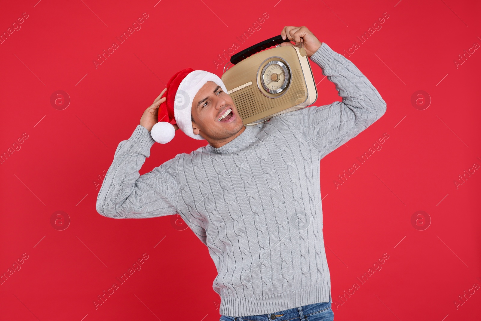 Photo of Emotional man with vintage radio on red background. Christmas music