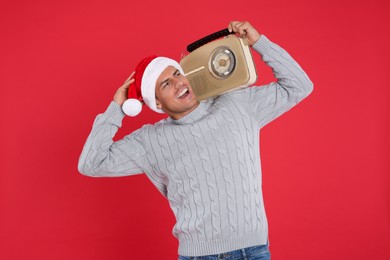 Emotional man with vintage radio on red background. Christmas music