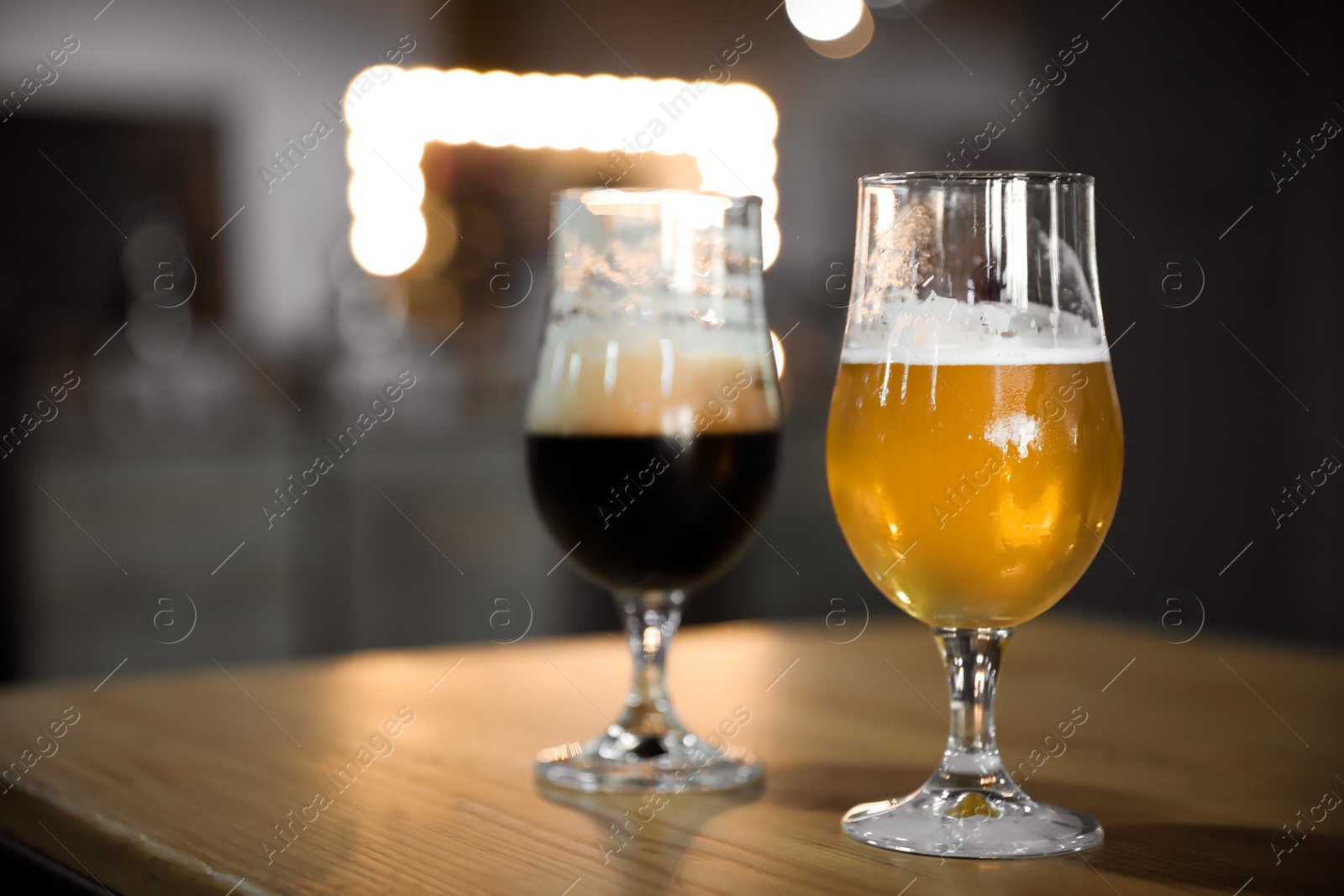 Photo of Cold tasty light and dark beer on table indoors. Space for text