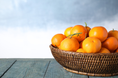 Photo of Fresh ripe tangerines on wooden table against light blue background. Space for text