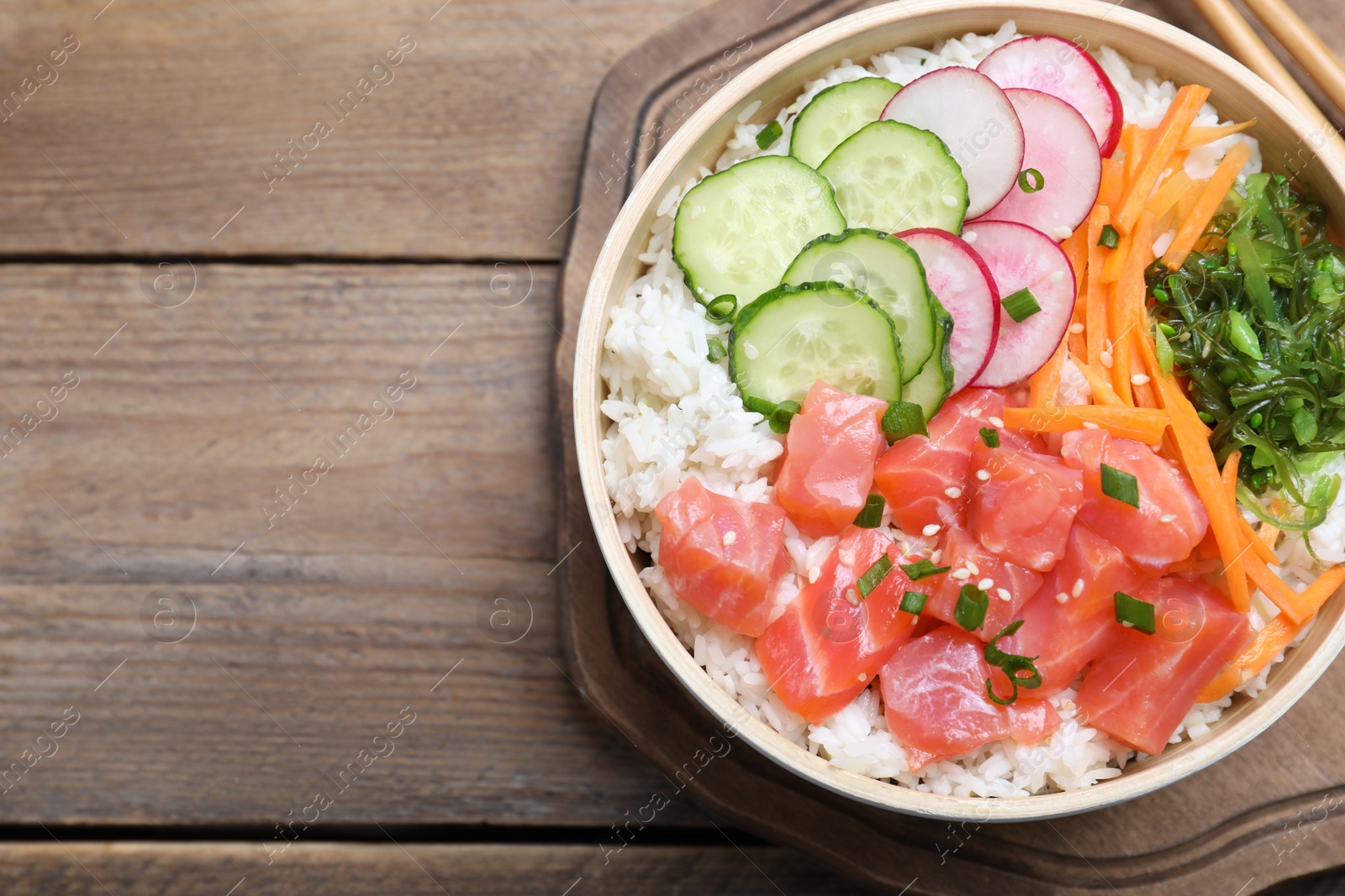 Photo of Delicious poke bowl with salmon and vegetables on wooden table, top view