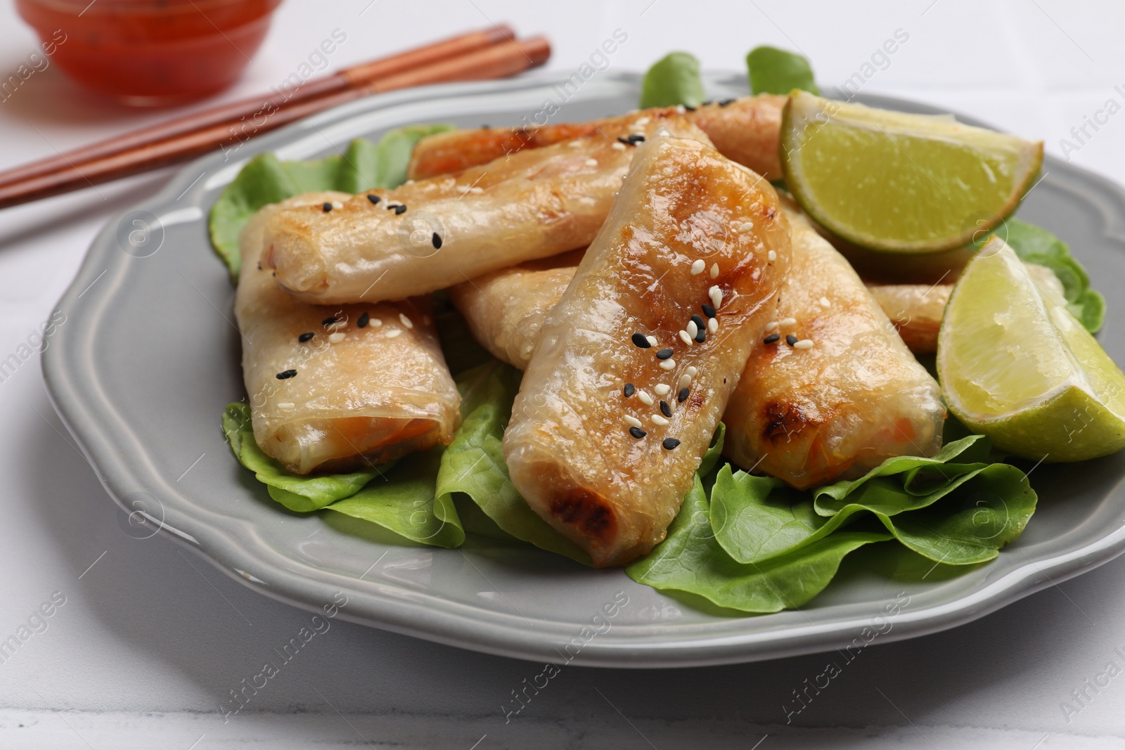 Photo of Tasty fried spring rolls served on light table, closeup