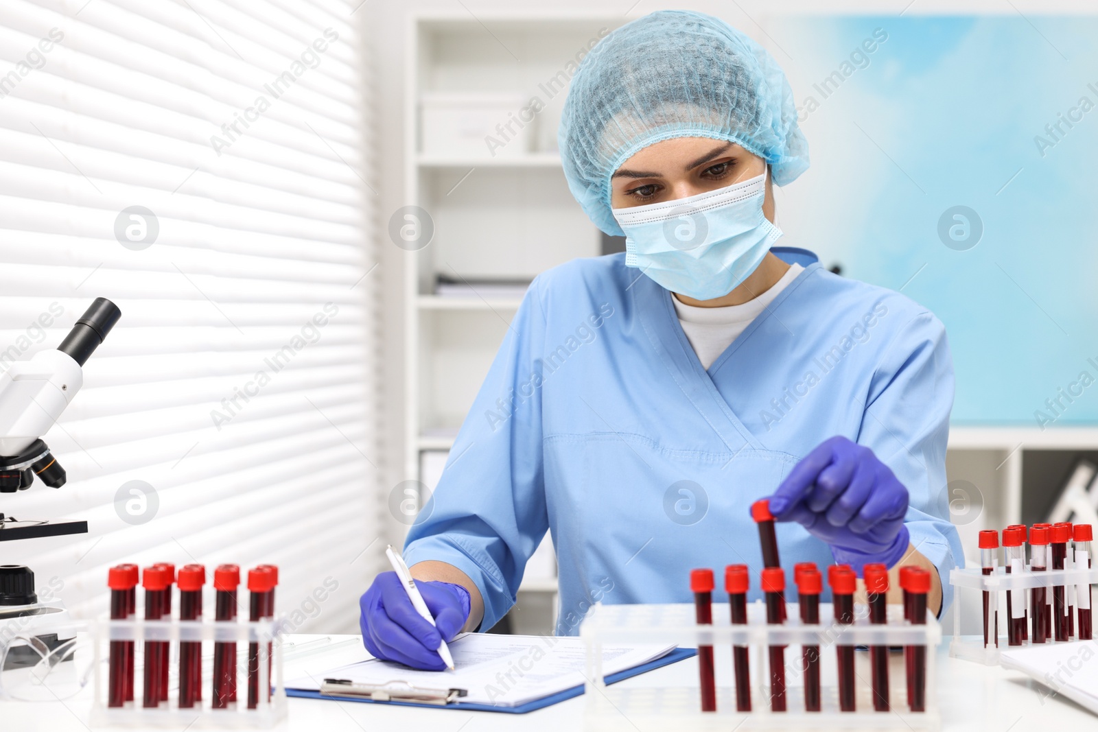 Photo of Laboratory testing. Doctor with blood samples in tubes at white table indoors