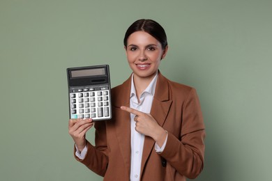 Smiling accountant with calculator on green background
