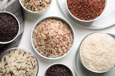 Photo of Different sorts of rice on white table, flat lay