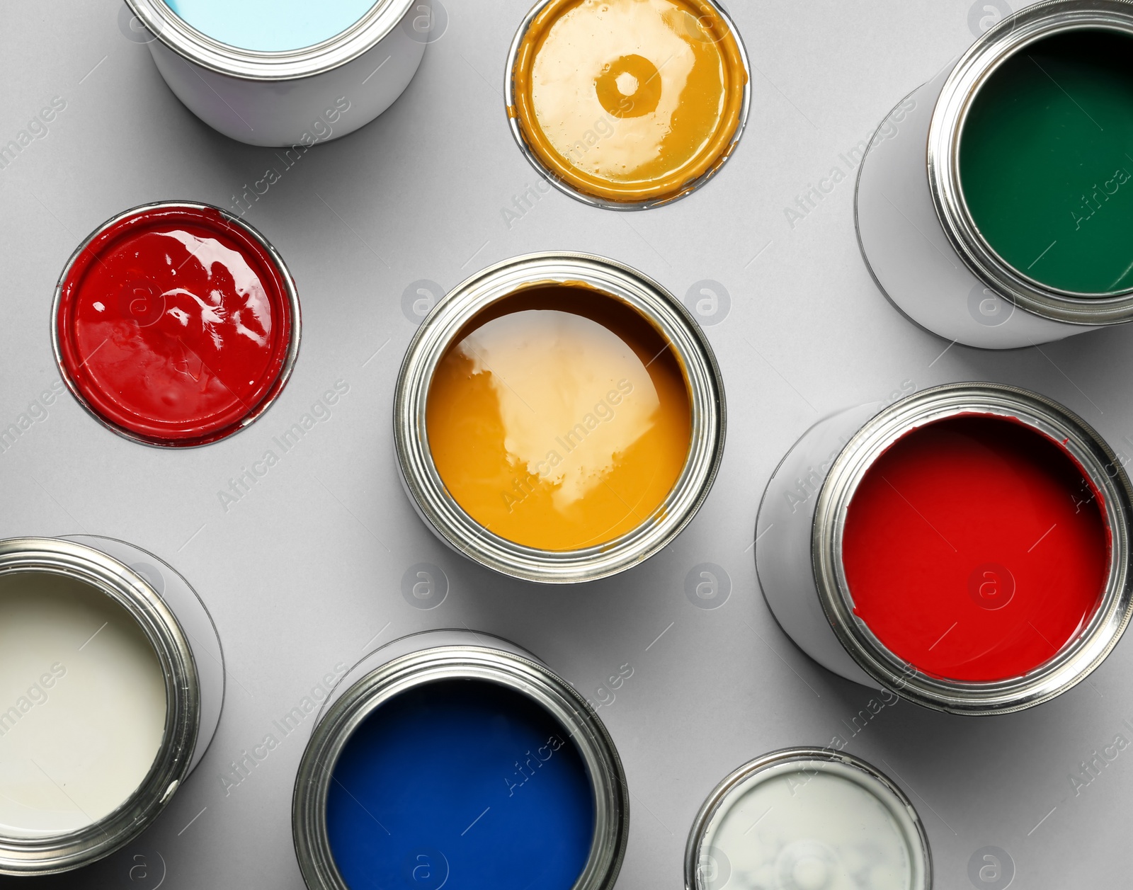 Photo of Open paint cans on grey background, top view