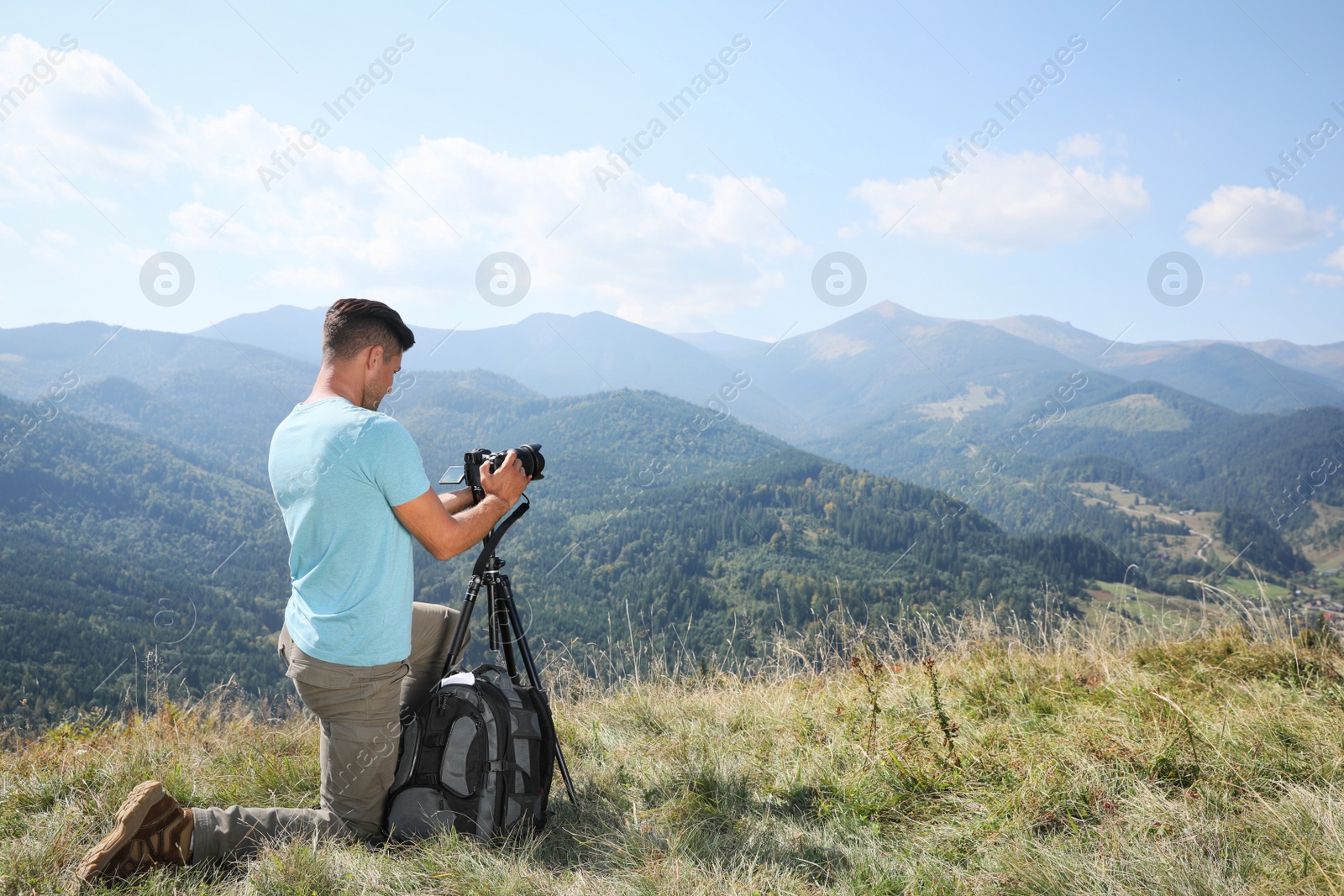 Photo of Professional photographer taking picture with modern camera in mountains. Space for text