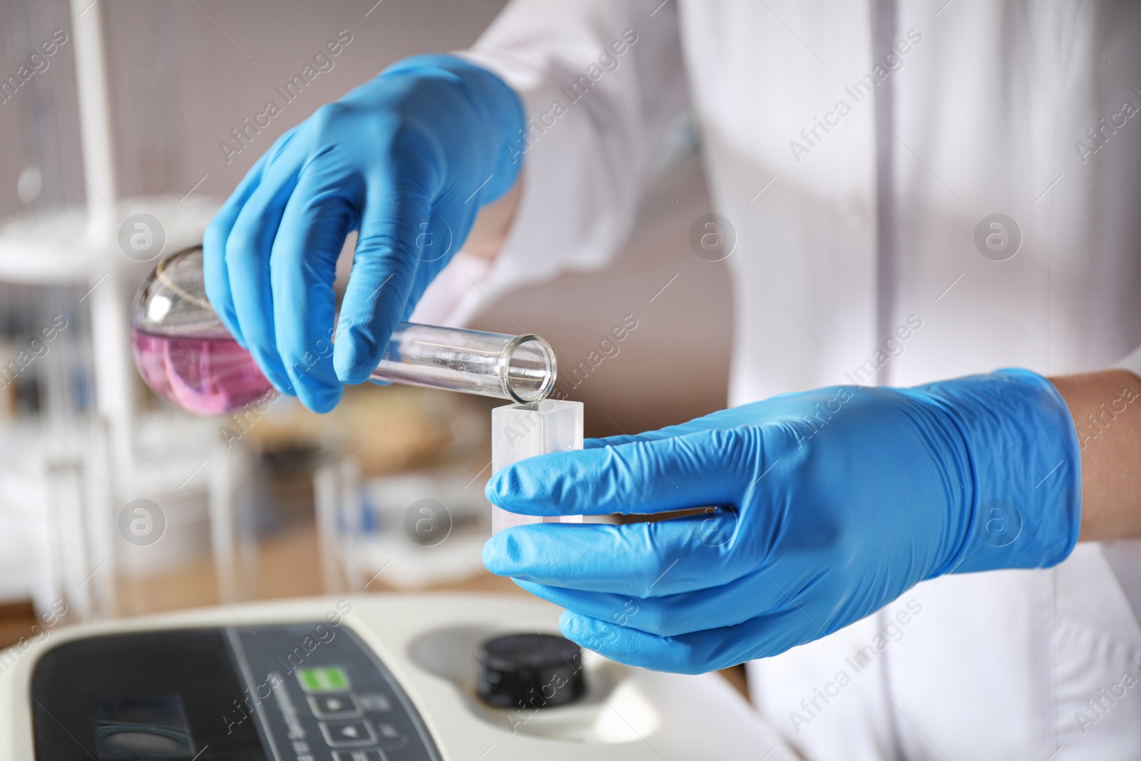 Photo of Scientist pouring colorful liquid into sample compartment in laboratory, closeup