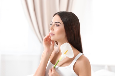 Photo of Portrait of young woman with calla flower indoors. Beauty and body care