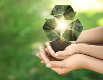 Image of Family holding fertile soil on blurred background and recycling symbol, closeup. Space for text 