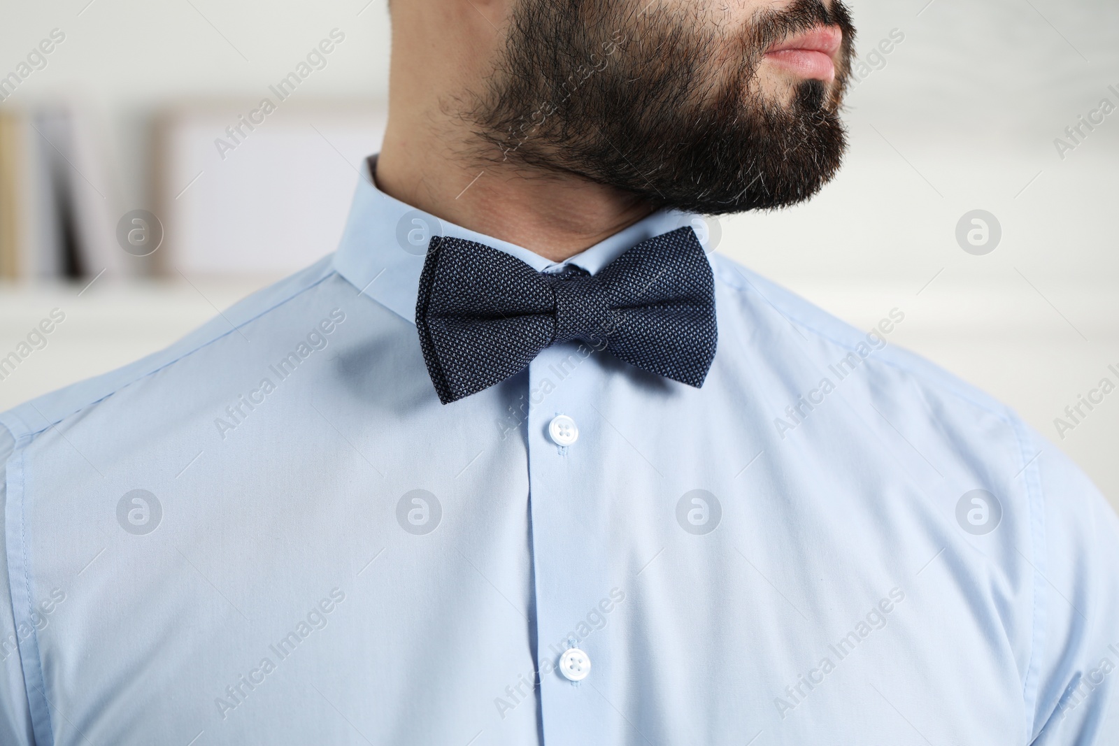 Photo of Man in shirt and bow tie indoors, closeup