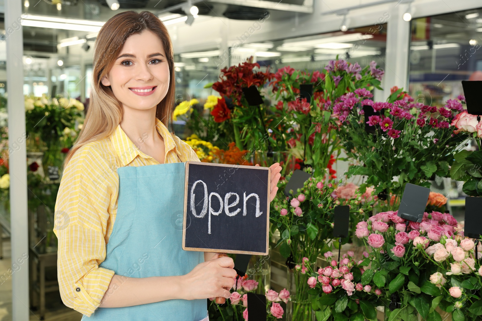 Image of Florist holding sign with text OPEN in shop