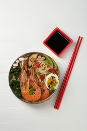 Photo of Delicious ramen with shrimps and egg in bowl served on white wooden table, flat lay. Noodle soup