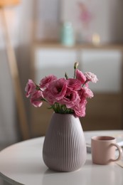 Photo of Vase with beautiful eustoma flowers on table in modern room interior