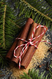 Different aromatic spices and fir branches on grey table, flat lay