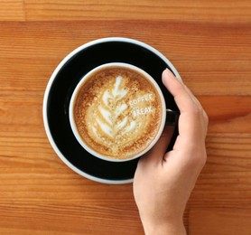 Image of Coffee Break. Woman with cup of cappuccino at wooden table, top view