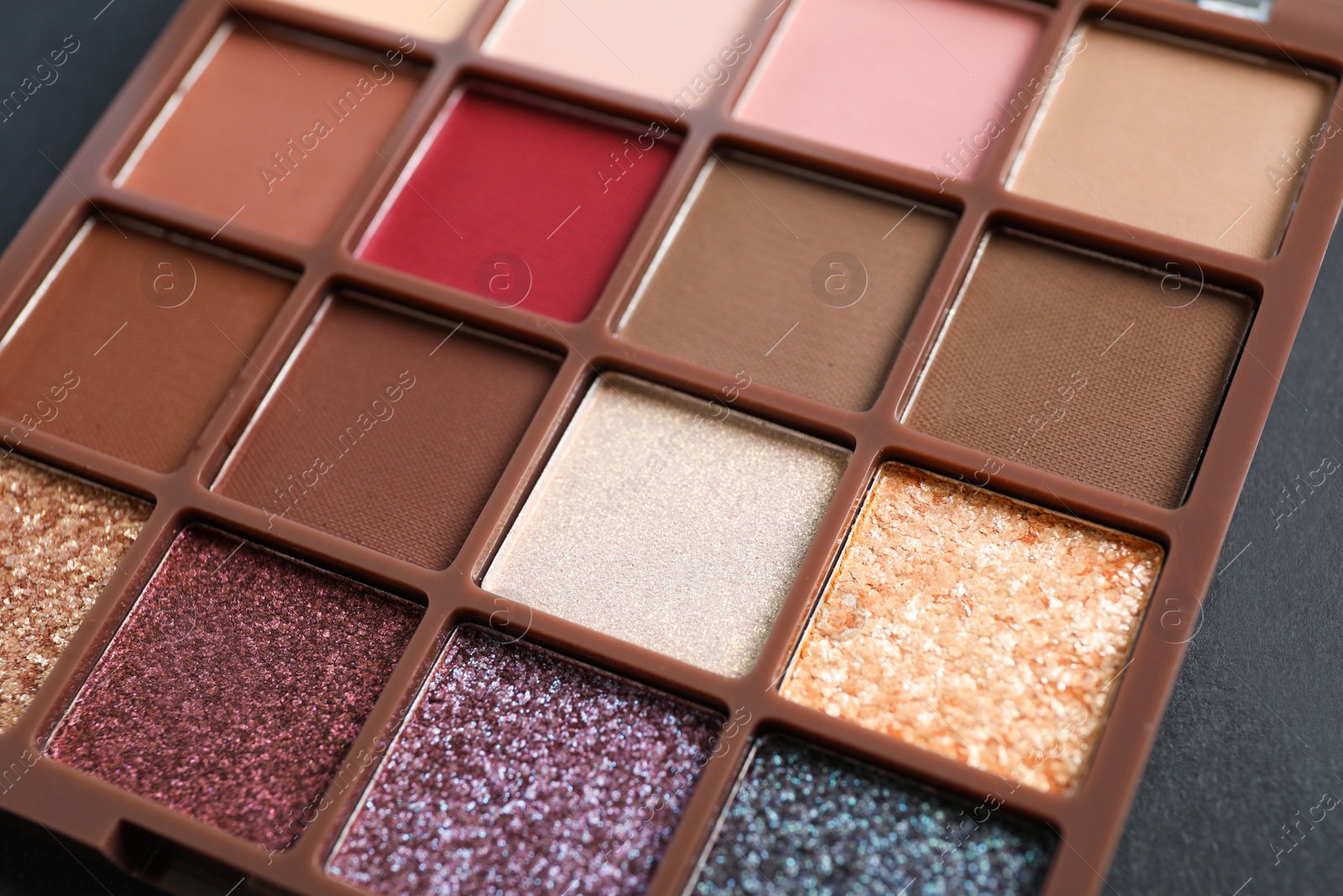 Photo of Colorful eyeshadow palette on dark background, closeup