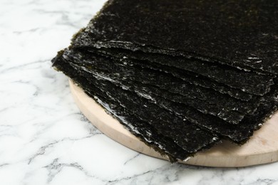 Photo of Dry nori sheets on white marble table, closeup