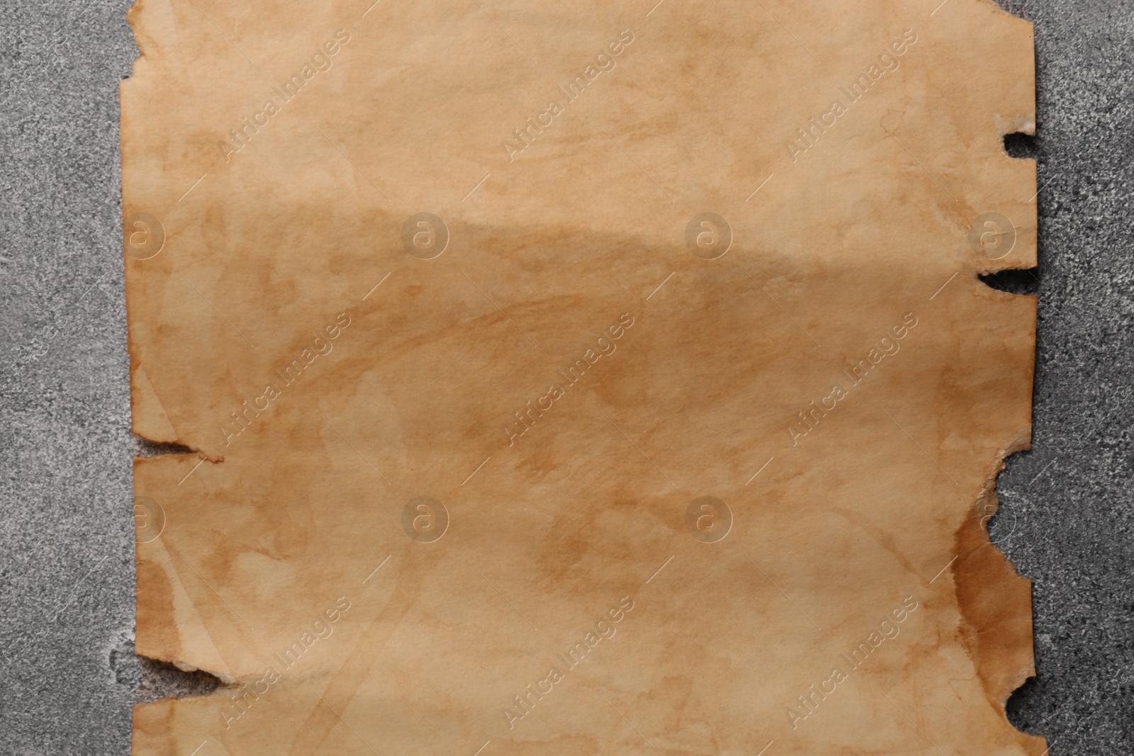 Photo of Sheet of old parchment paper on gray textured table, top view