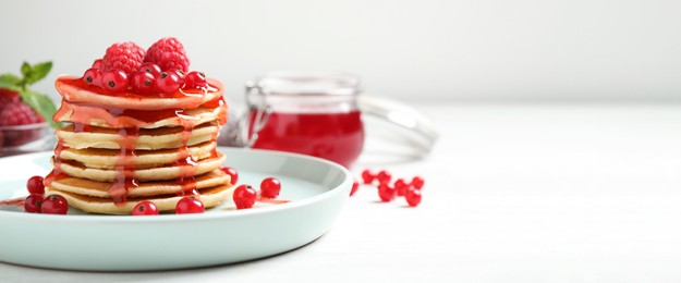 Delicious pancakes with fresh berries and syrup on white table, space for text. Banner design