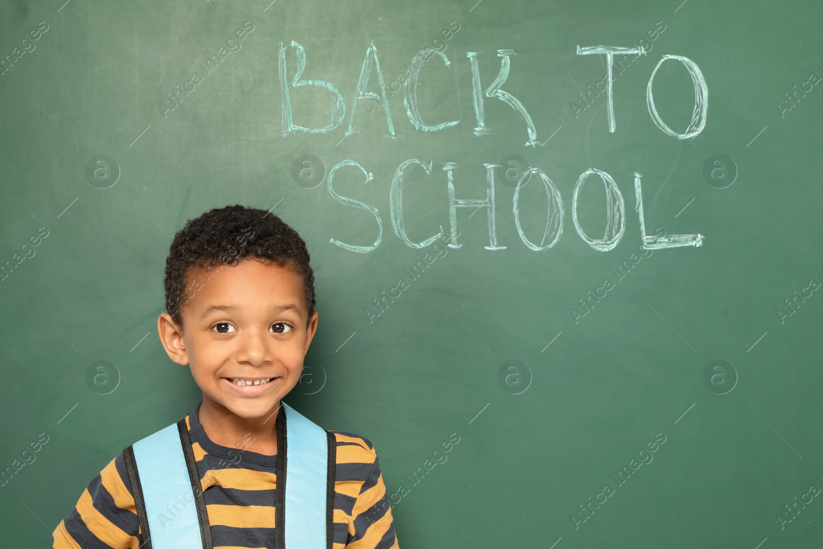 Photo of Little African-American child near chalkboard with text BACK TO SCHOOL