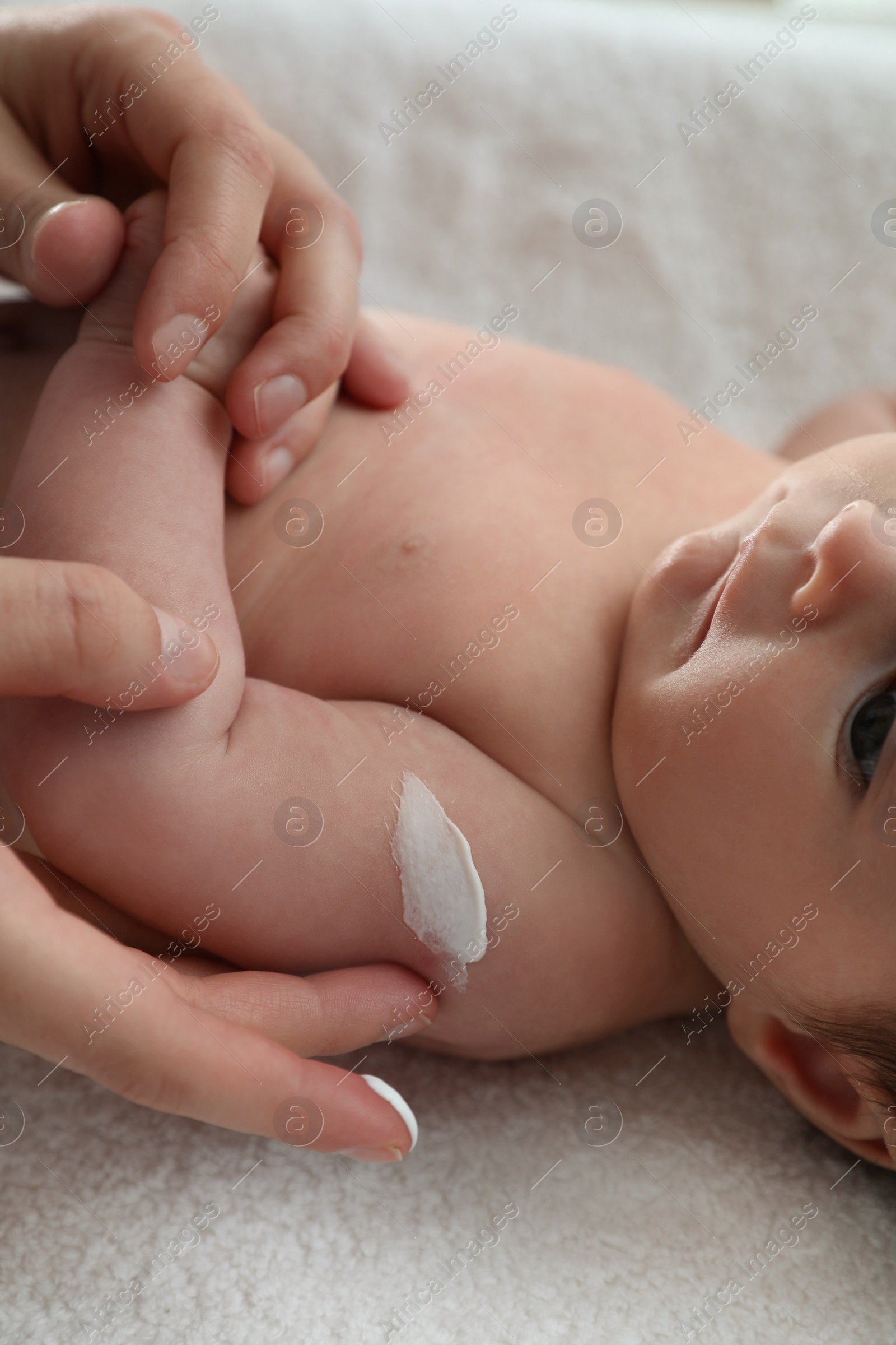 Photo of Mother applying body cream on her little baby, closeup