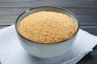 Photo of Brown sugar in bowl on black wooden table, closeup