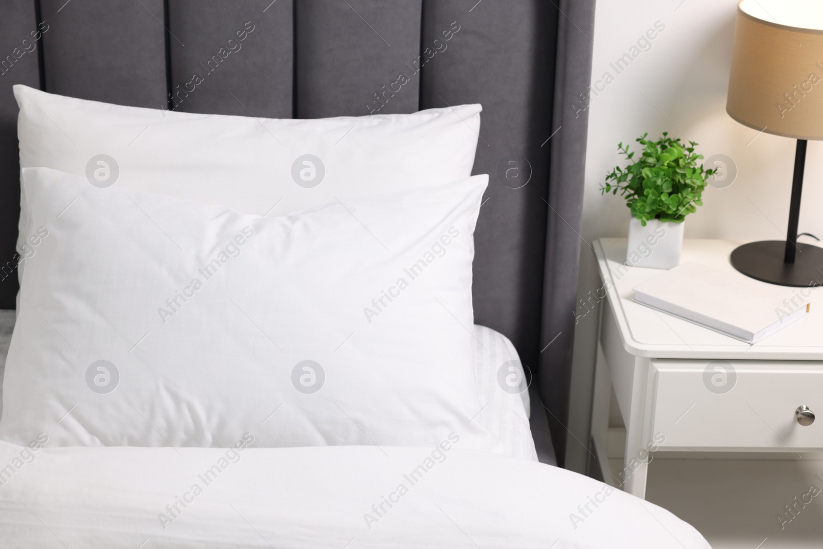 Photo of Soft white pillows and duvet on bed at home