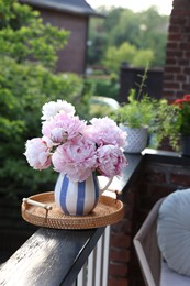 Beautiful pink peony flowers in vase on balcony railing outdoors