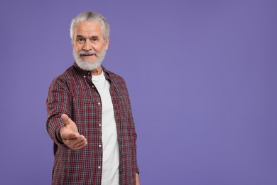 Photo of Senior man welcoming and offering handshake on purple background, space for text