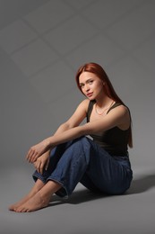 Photo of Beautiful young woman sitting on gray background