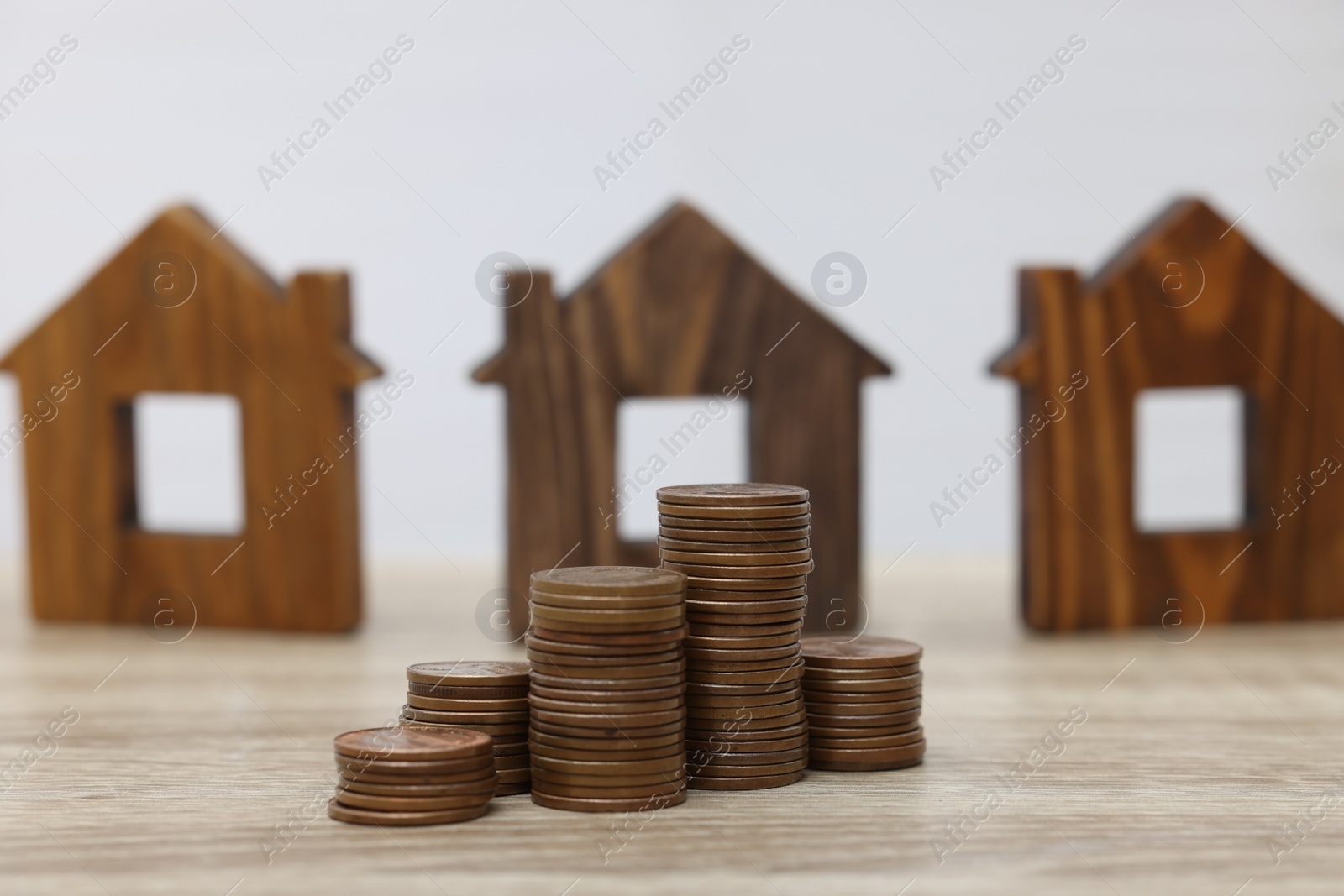 Photo of House models and stacked coins on wooden table