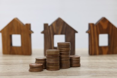 House models and stacked coins on wooden table