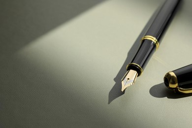 Stylish fountain pen on light grey textured table, closeup. Space for text