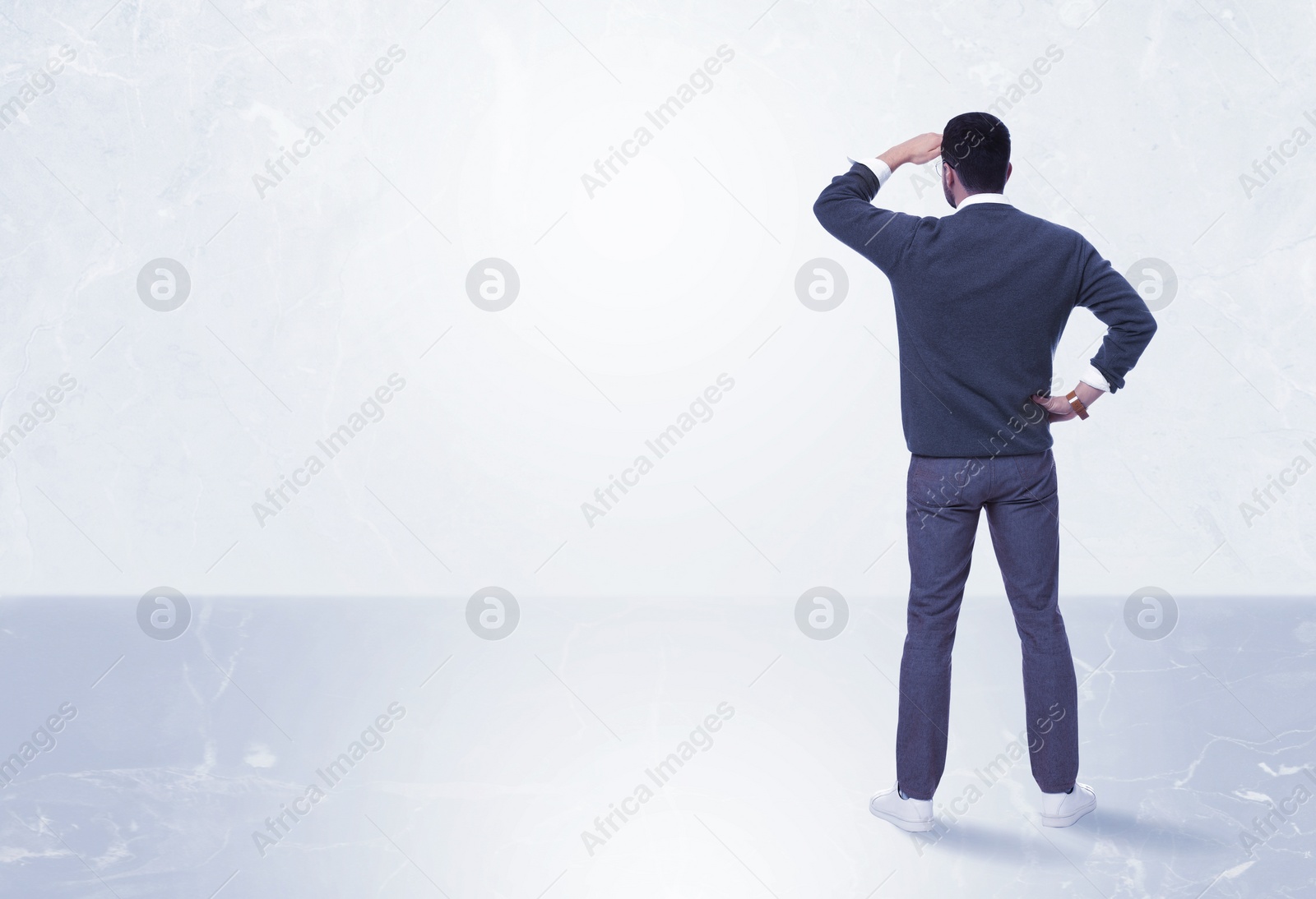 Image of Man standing in front of light marble wall, back view. Space for text