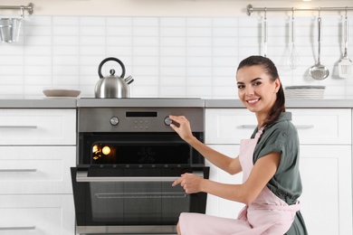 Photo of Young woman baking something in oven at home