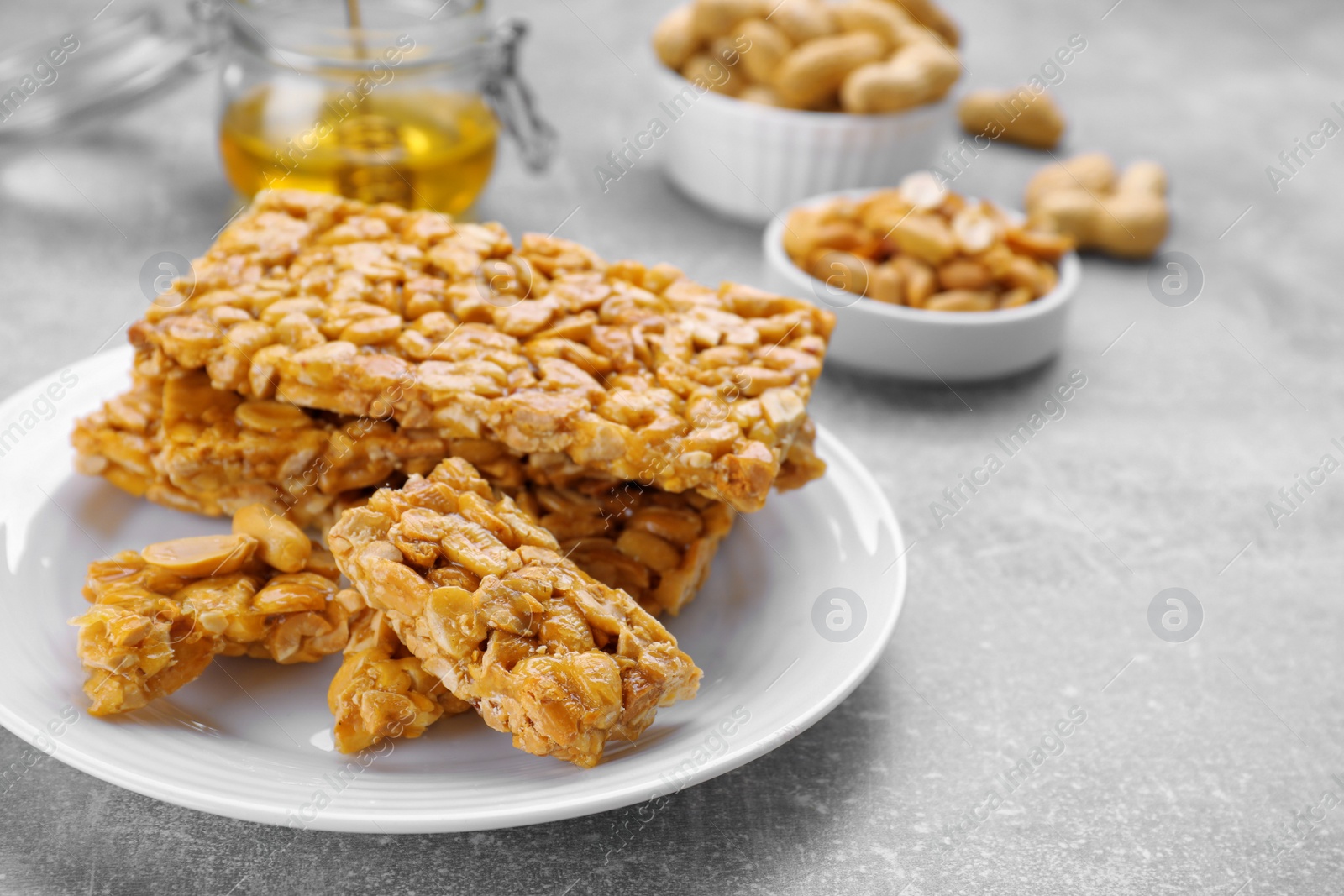 Photo of Delicious peanut kozinaki bars on light gray textured table, closeup. Space for text