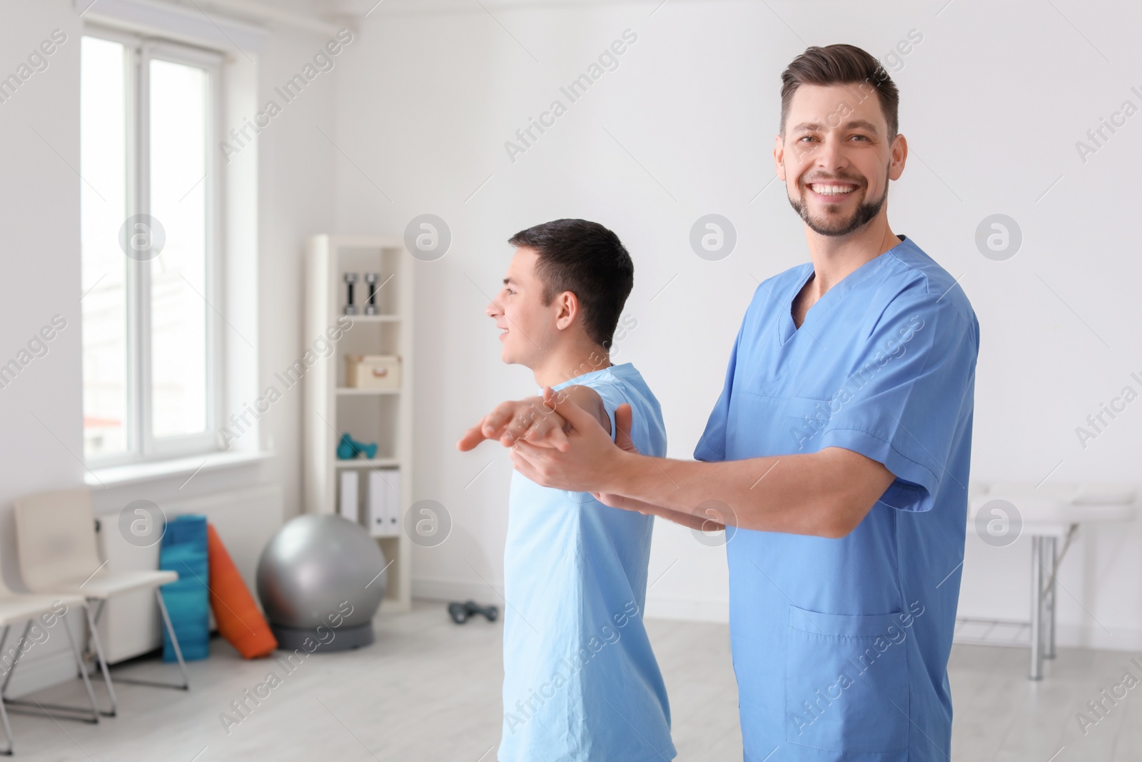 Photo of Physiotherapist working with male patient in clinic