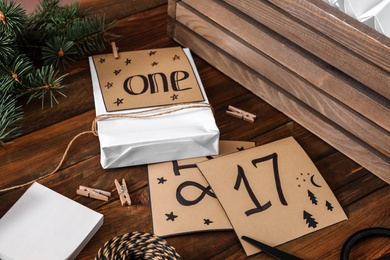 Photo of Composition with gift bag and paper notes on wooden table, closeup. Creating advent calendar