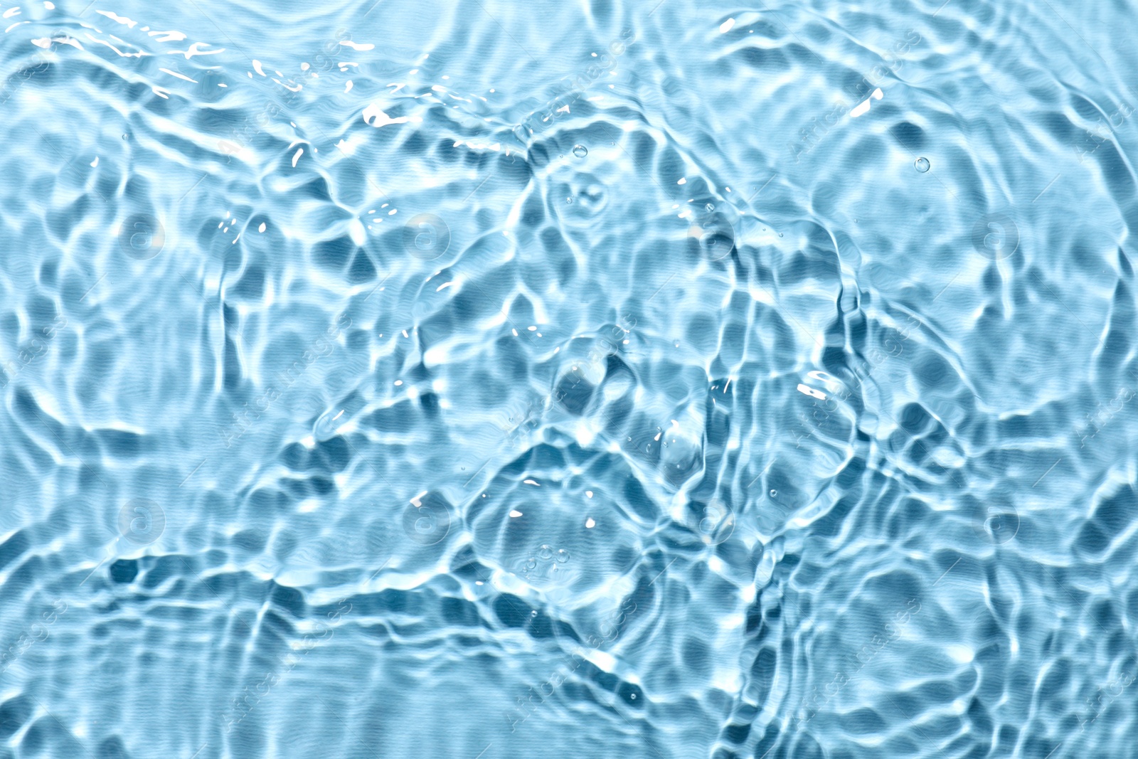 Photo of Rippled surface of clear water on light blue background, top view