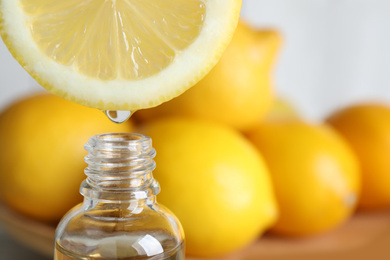 Photo of Citrus essential oil dripping from lemon slice into bottle, closeup. Space for text
