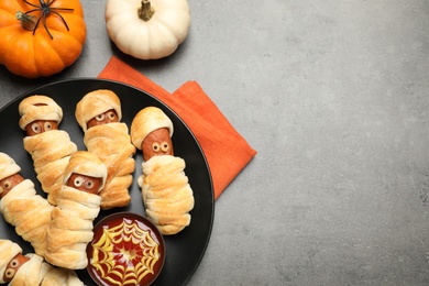 Spooky sausage mummies for Halloween party served on grey table, flat lay. Space for text