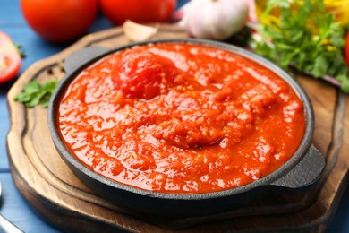 Homemade tomato sauce in bowl on blue table, closeup