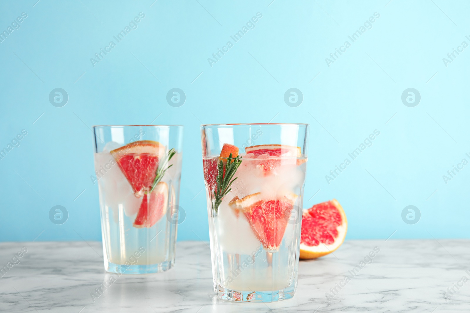 Photo of Glasses of infused water with grapefruit slices on table against color background. Space for text